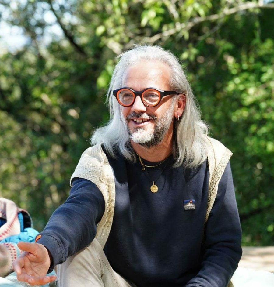 Portrait de Clément Victor, assis en extérieur, la main tendue